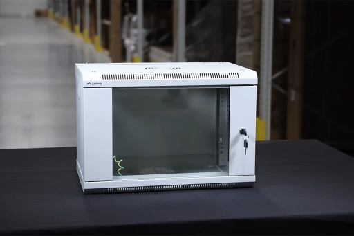 Biała wisząca szafa rack z przeszklonymi drzwiczkami i zamkiem stojąca na czarnym stole w magazynie.